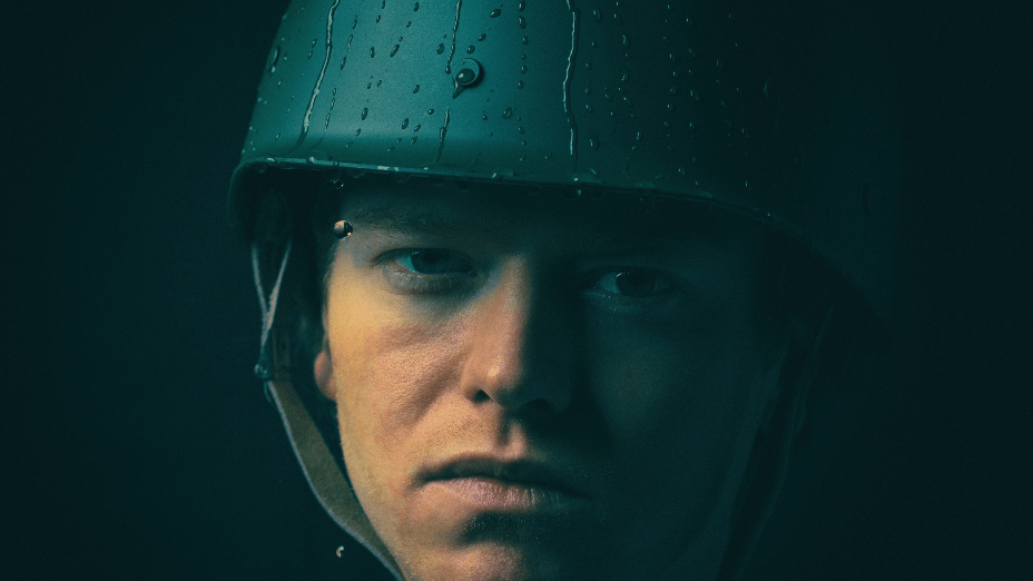 A soldier looks at the camera in his army helmet.